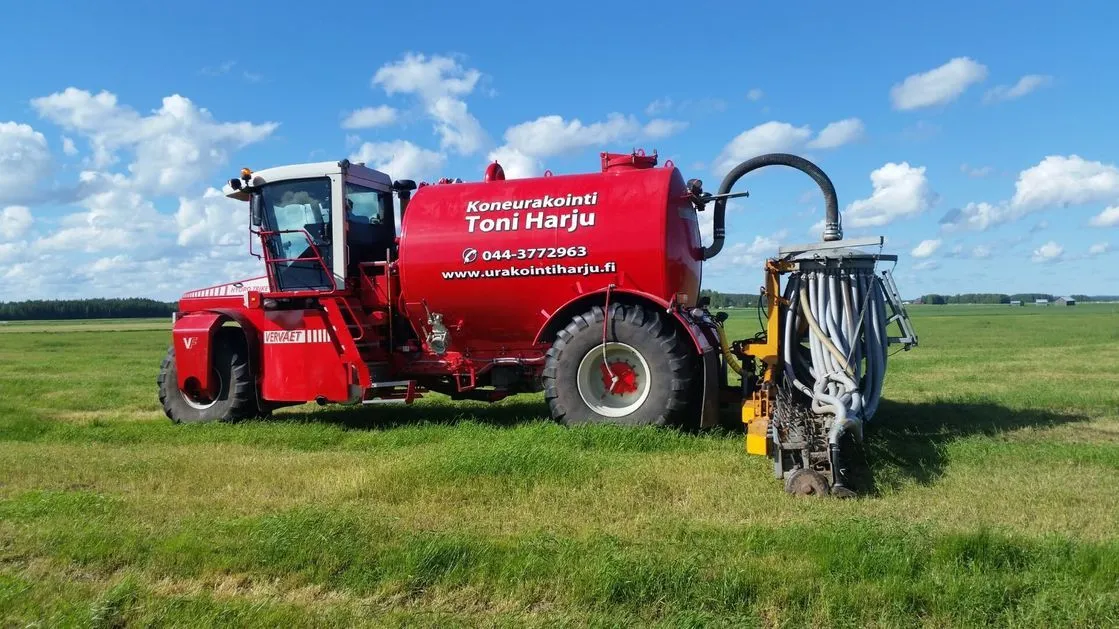 Punainen lietteenlevitin peltoalueella sinisen pilvettömän taivaan alla.