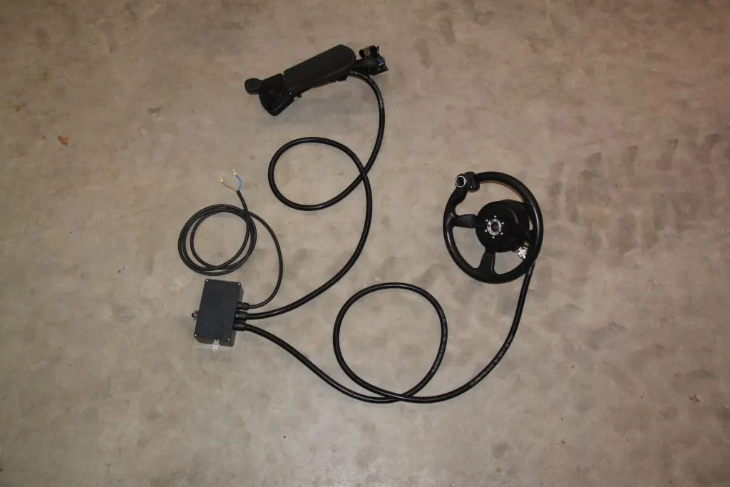 Mustia kaapeleita ja ohjauspyörän kaltaisia laitteita betonilattialla.