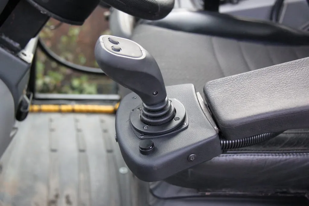 Ohjainsauva ja käsinoja mustassa ajoneuvon ohjaamossa.