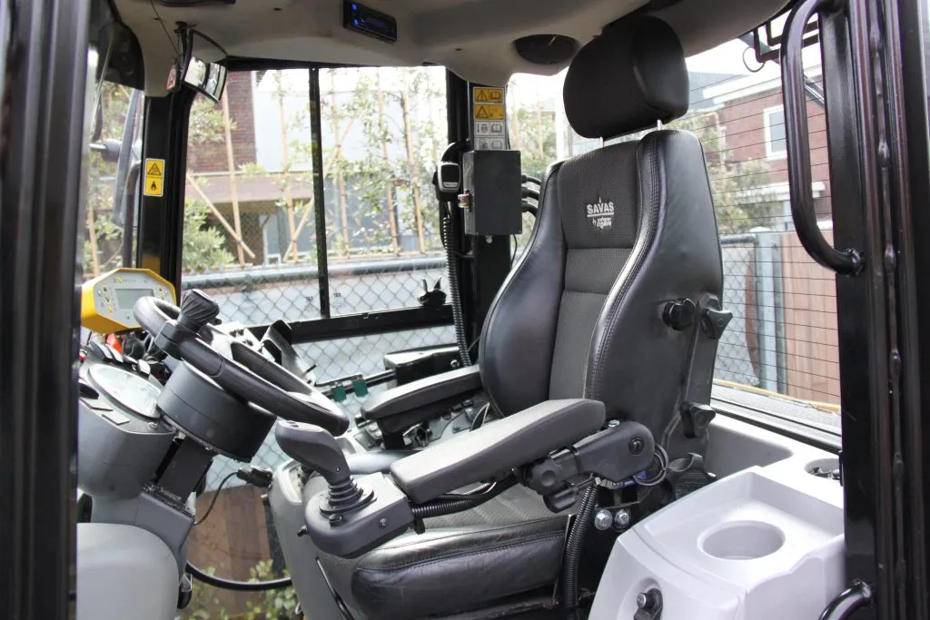 Ohjaamon sisätila raskaan koneen musta nahkainen kuljettajanistuin ja ohjauspyörä.