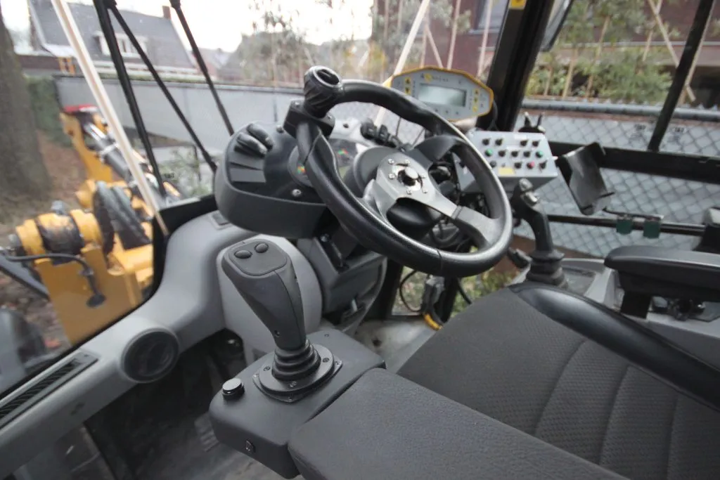 Ohjaamon sisätila, jossa on auton ohjauspyörä ja joystick-ohjain sekä näyttö ja useita painikkeita.