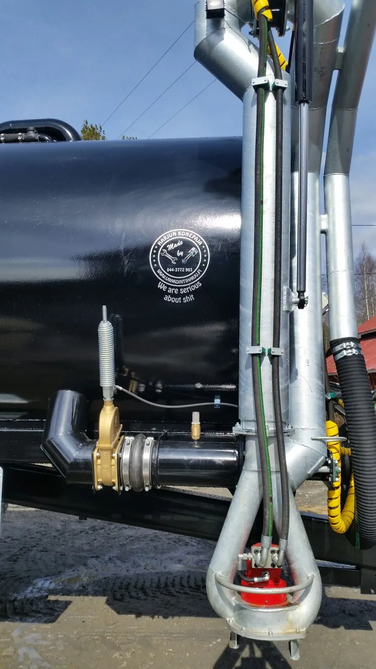 Musta säiliö ja siihen kiinnitettyjä metalliputkia ja musta letku ulkona kirkkaana päivänä.