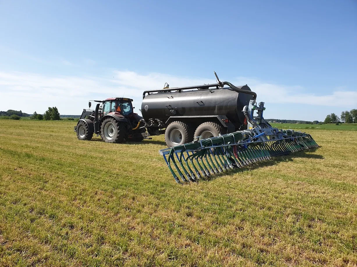 Traktori ja suuri keinolannoitesäiliö pellolla aurinkoisena päivänä.