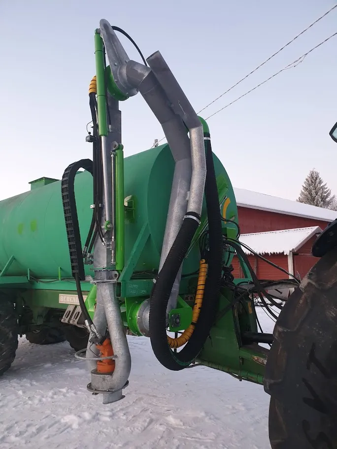 Vihreä lietelannankuljetusvaunu, jossa näkyy suuri imuletku ja maassa lunta.