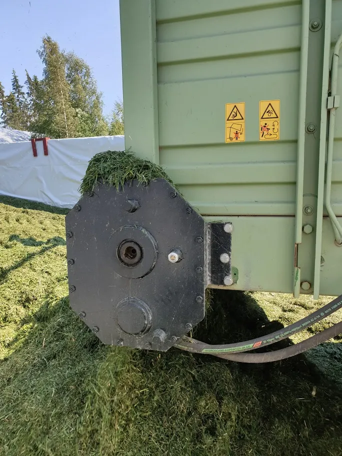 Palanut ruohoa ja leikkurin metalliosa, jossa varoitustarrat, ulkona aurinkoisena päivänä.